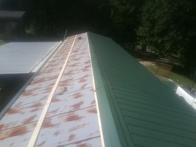 Old rusted panels beside newly installed green metal roofing — Wind Damage Roof Repair by Roofing Brothers in Crows Landing