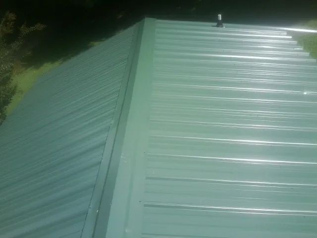 New green metal panels meeting at the ridge of a roof — Flat Roof Repair work by our crew in Crows Landing
