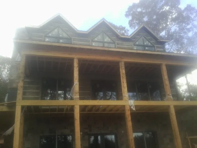 Dormers and porch framing on a large log home under construction — Roof Coating work by our crew in Crows Landing
