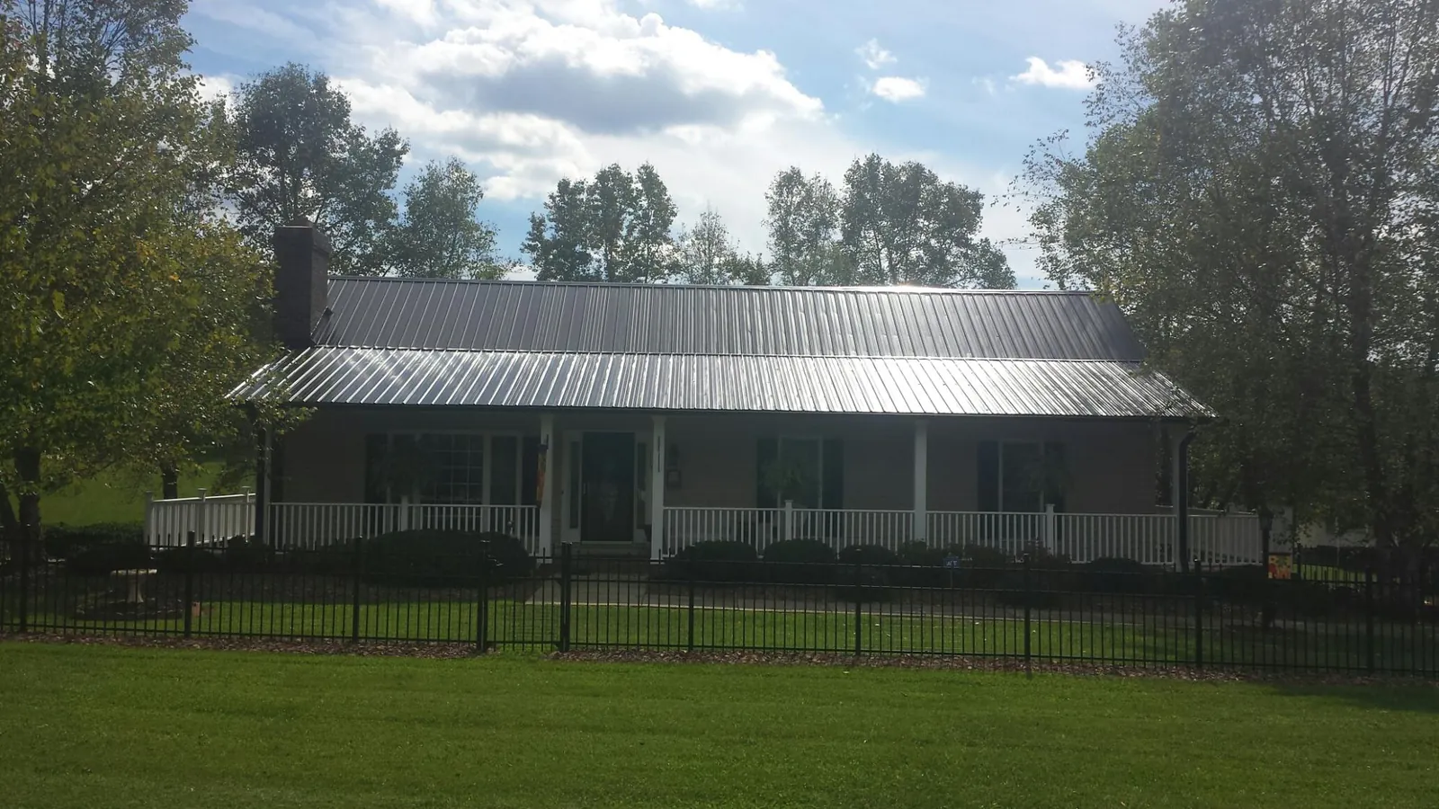 Gray metal roof on a brick ranch with a full width front porch — Gutter Guard Installation work by our crew in Crows Landing