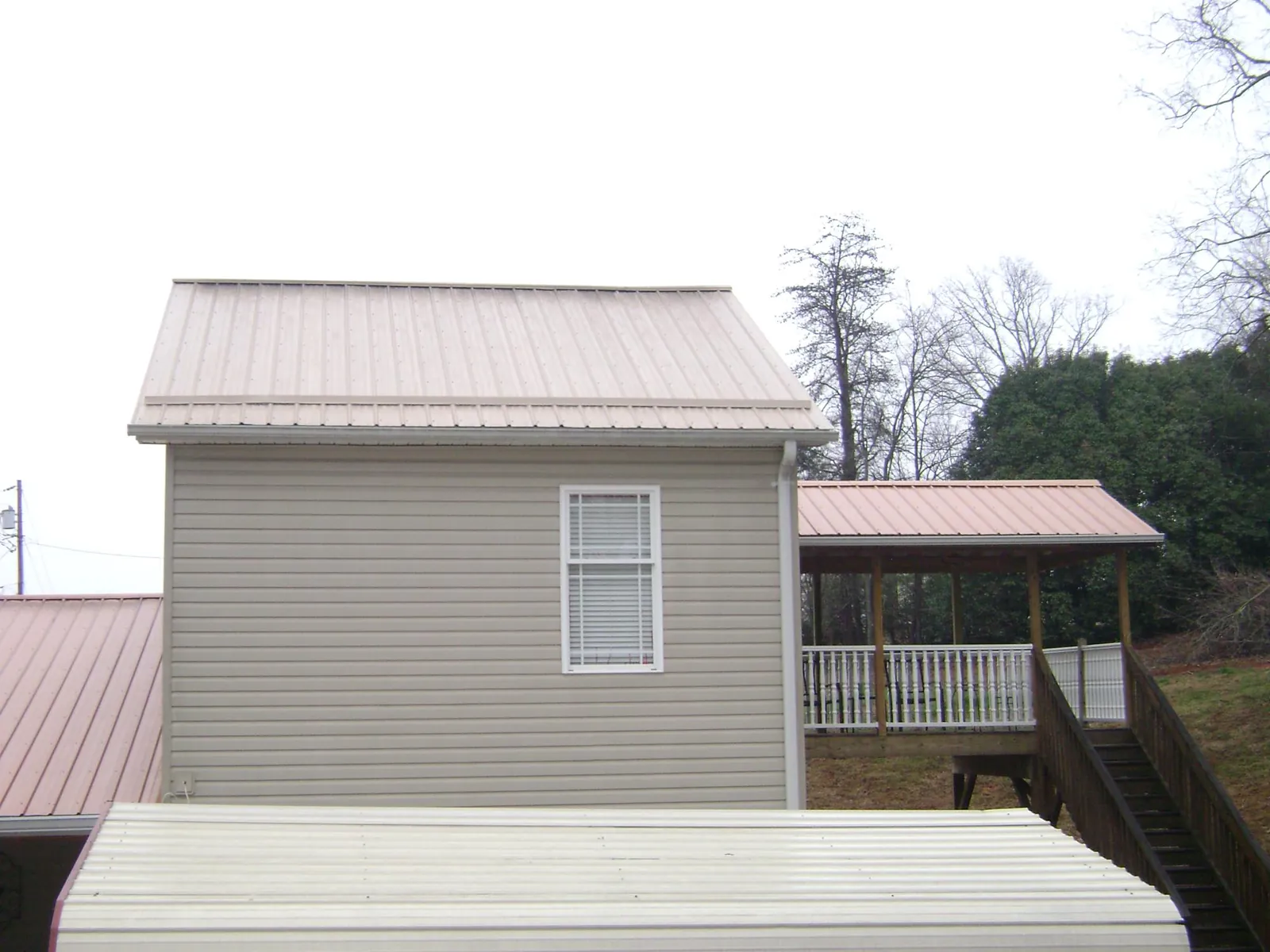 Tan metal roofs on a two story addition and attached porch, from a Roof Replacement job in Crows Landing